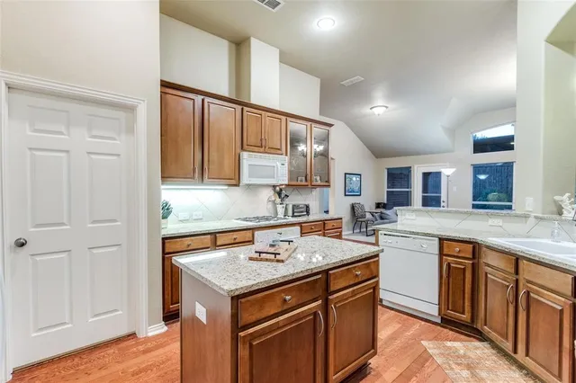 a kitchen with stainless steel appliances granite countertop a sink dishwasher a stove and a dining table with wooden floor