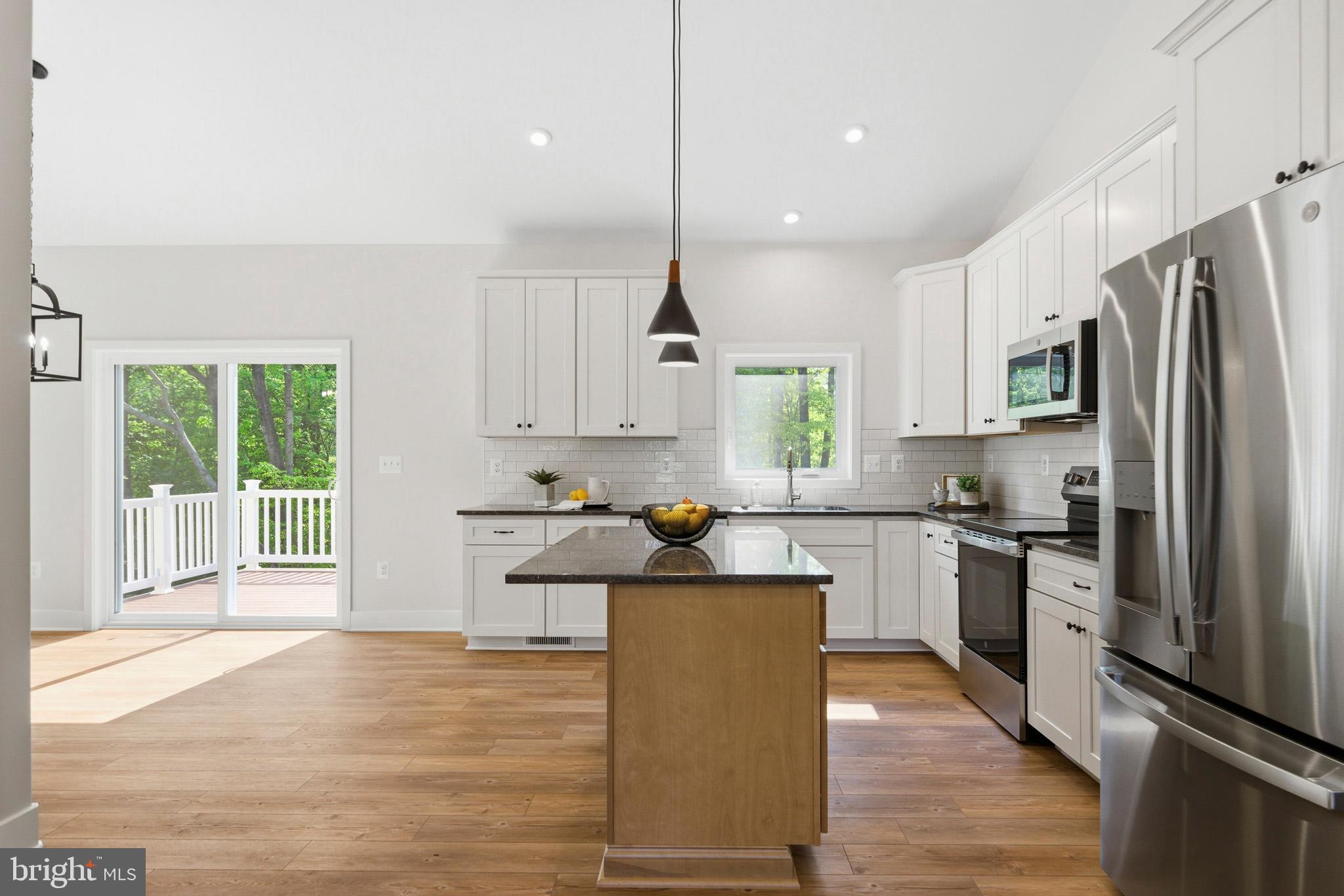 1362 Solomons Island Road Huntingtown, MD 20639 - Photo 11 of 37 a kitchen with stainless steel appliances granite countertop a refrigerator a sink dishwasher a stove top oven a large island with wooden floor and cabinets