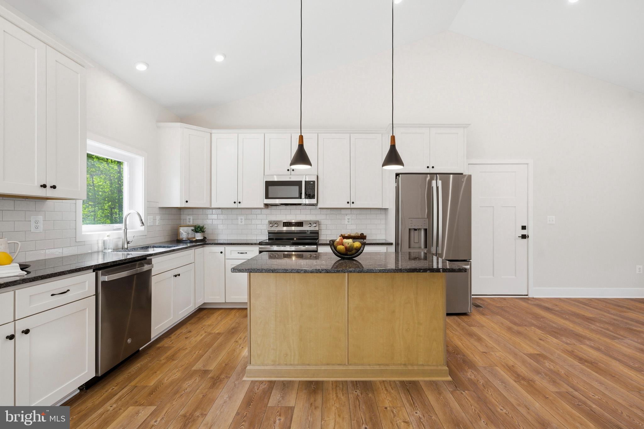 1362 Solomons Island Road Huntingtown, MD 20639 - Photo 12 of 37 a kitchen with stainless steel appliances granite countertop a sink a stove and white cabinets with wooden floor
