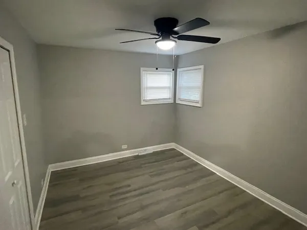 an empty room with wooden floor chandelier fan and window