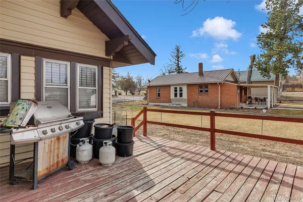 a view of a roof deck with table and chairs couches with wooden floor and fence