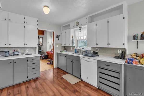 a kitchen with cabinets appliances wooden floor and a window