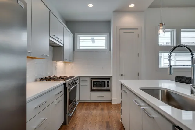 a kitchen with a stove a sink and wooden floor