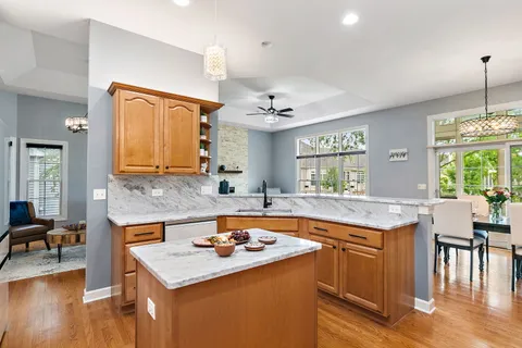 a kitchen with a stove a sink dishwasher a dining table and chairs with wooden floor