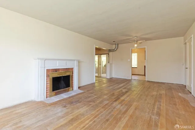 a view of empty room with wooden floor and fireplace