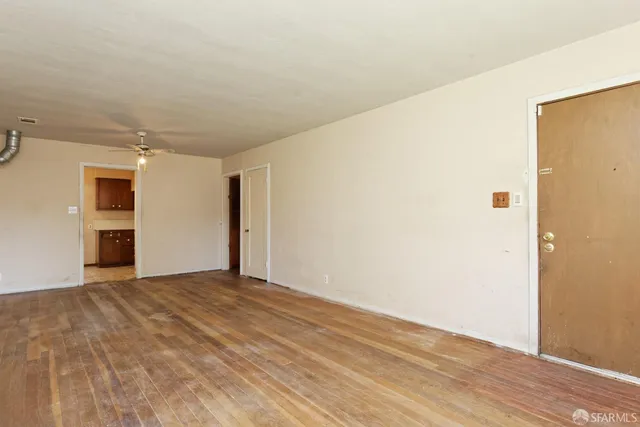 a view of an empty room with wooden floor and closet