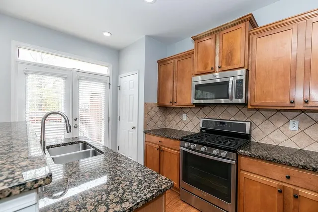 a kitchen with stainless steel appliances granite countertop a stove a sink and a microwave