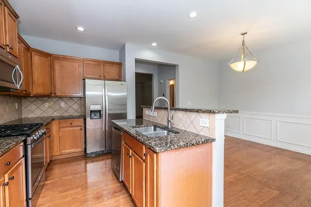 a kitchen with stainless steel appliances granite countertop a sink a stove and a refrigerator