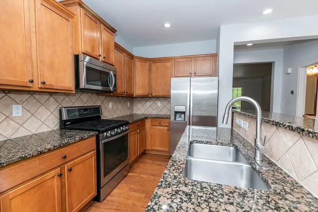 a kitchen with stainless steel appliances granite countertop a sink a stove top oven and granite counter tops