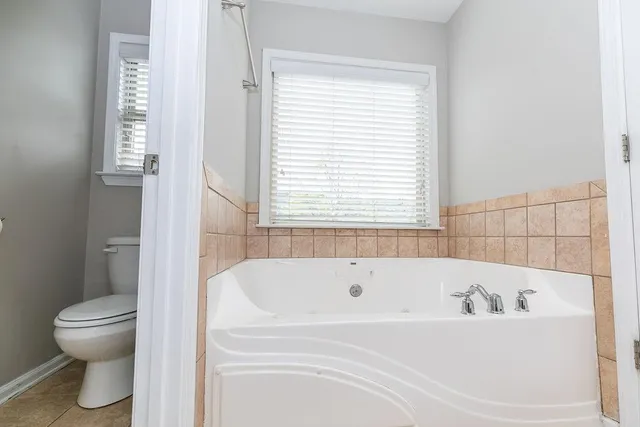 a bathroom with a granite countertop sink a mirror a bathtub and next to a window