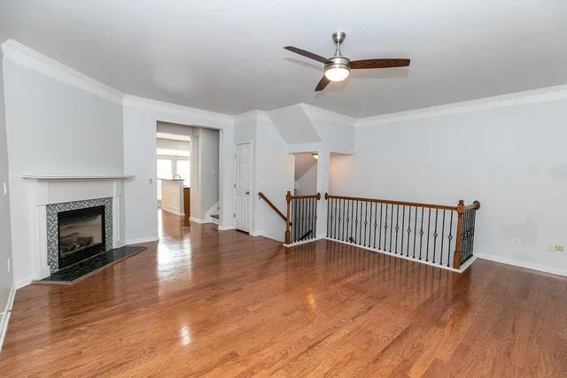 a view of an empty room with wooden floor a fireplace and a window