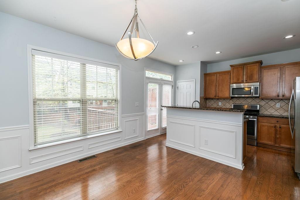 827 Charles Bank Avenue Southeast, Unit 827 Atlanta, GA 30312 - Photo 10 of 45 a kitchen with stainless steel appliances granite countertop a stove a refrigerator a sink a microwave oven with white cabinets and wooden floor
