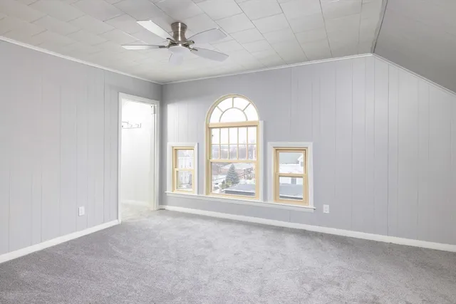 an empty room with windows and ceiling fan