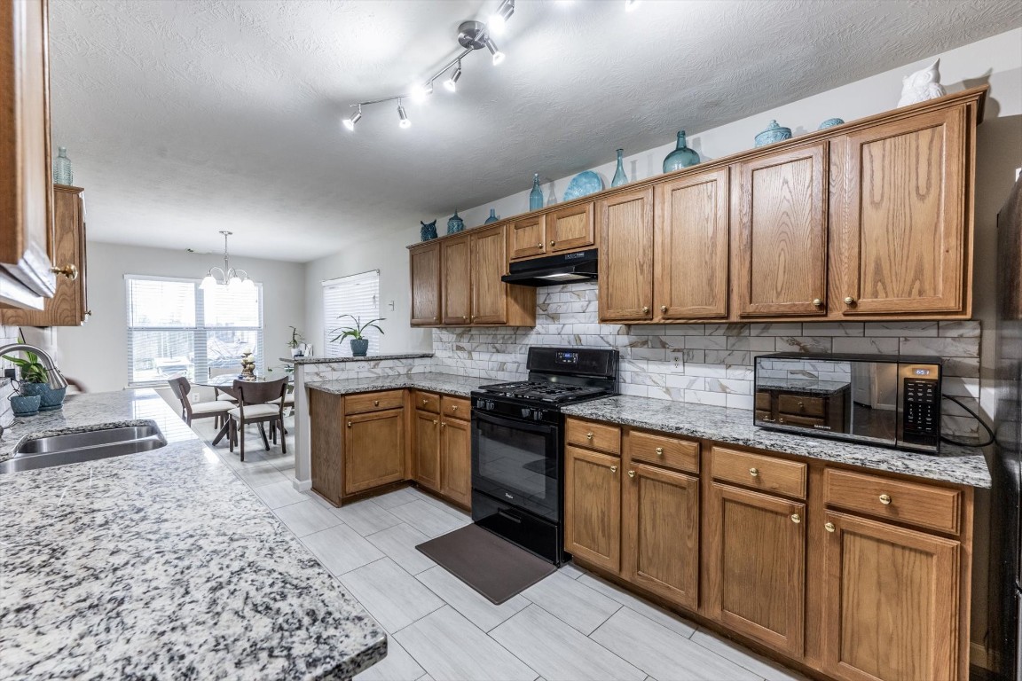 13507 Beech Ridge Lane Houston, TX 77083 - Photo 15 of 49 a kitchen with stainless steel appliances granite countertop wooden cabinets a stove top oven a sink and dishwasher