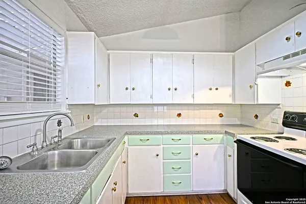 a kitchen with granite countertop a sink a stove and cabinets