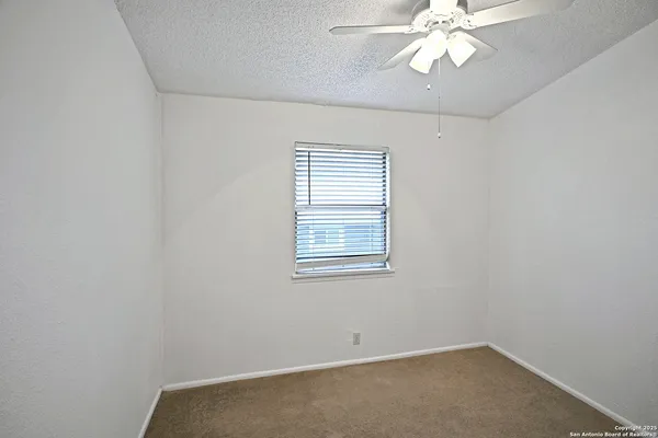 an empty room with a window and a fan