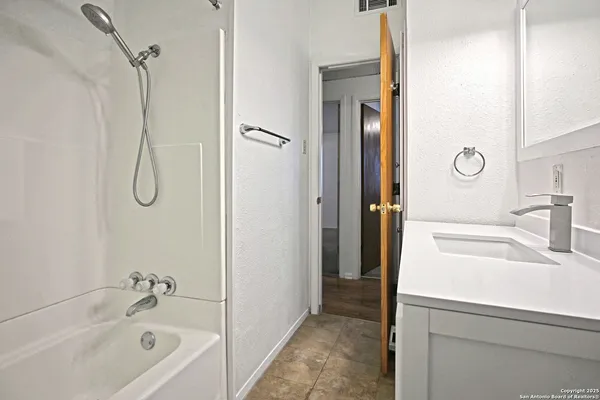 a bathroom with a tub sink vanity and shower