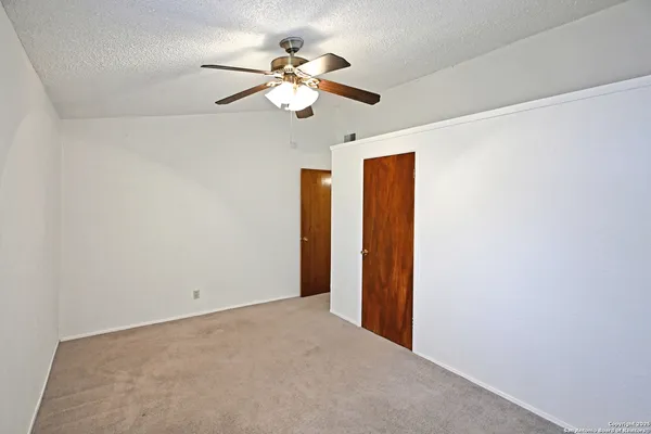 an empty room with a chandelier fan and closet