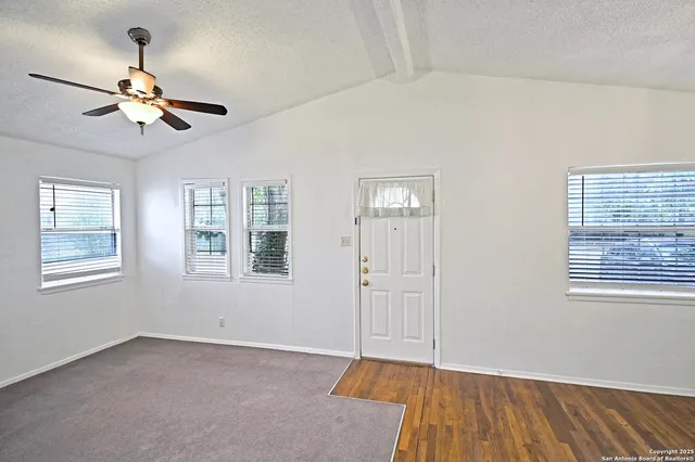 a view of an empty room with a window and wooden floor