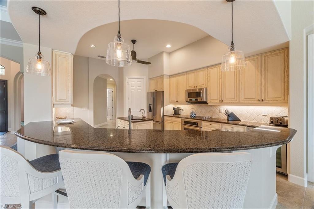 12130 Wicklow Lane Naples, FL 34120 - Photo 14 of 45 a kitchen with stainless steel appliances granite countertop a sink a center island and cabinets