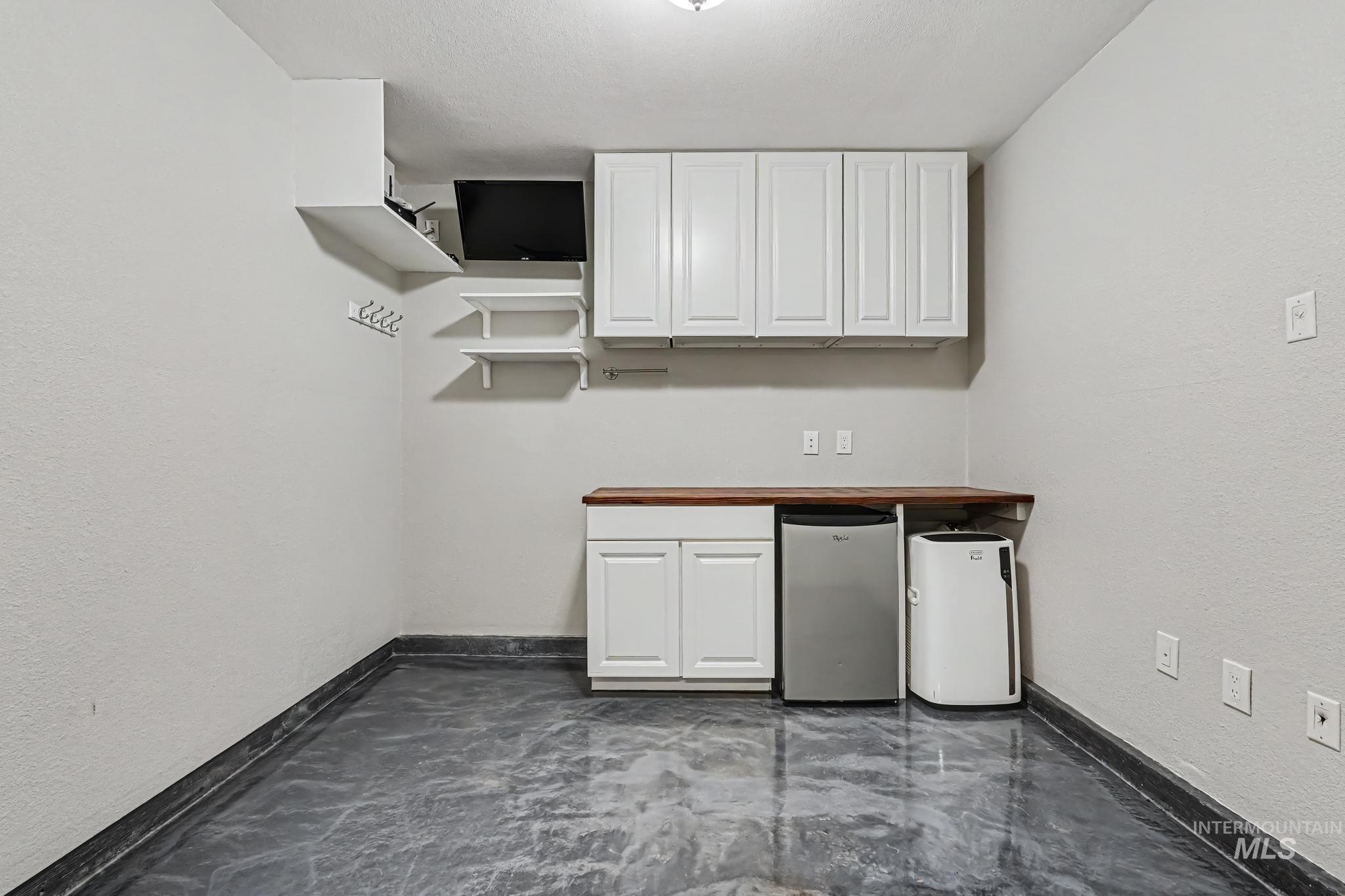 14421 West Stockwell Street Boise, ID 83713 - Photo 15 of 20 Utility area featuring white cabinetry, a wood-finish countertop, and durable epoxy flooring