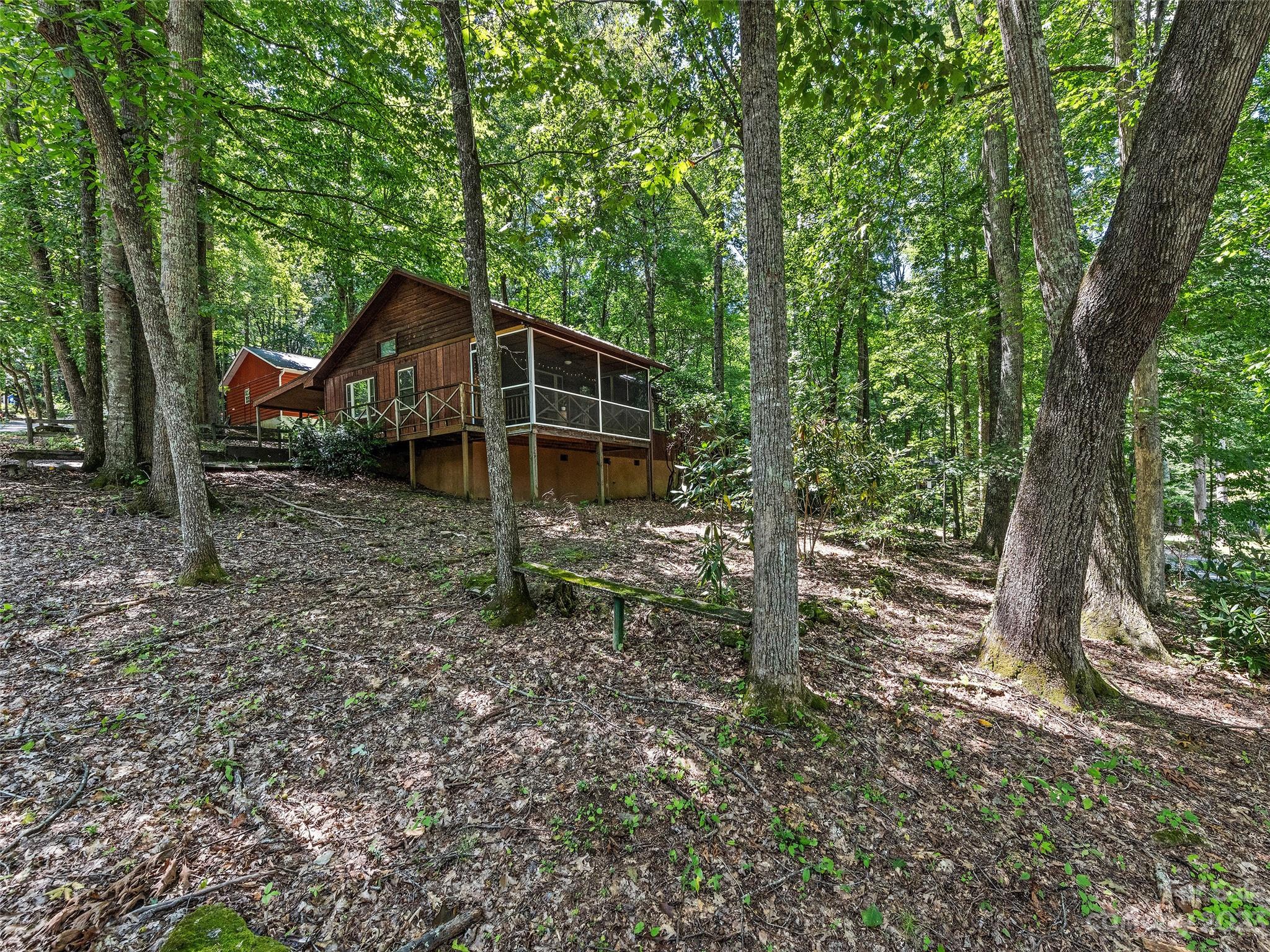 260 Reuben Branch Road Maggie Valley, NC 28751 - Photo 3 of 24 a view of a wooden house with a yard and large trees