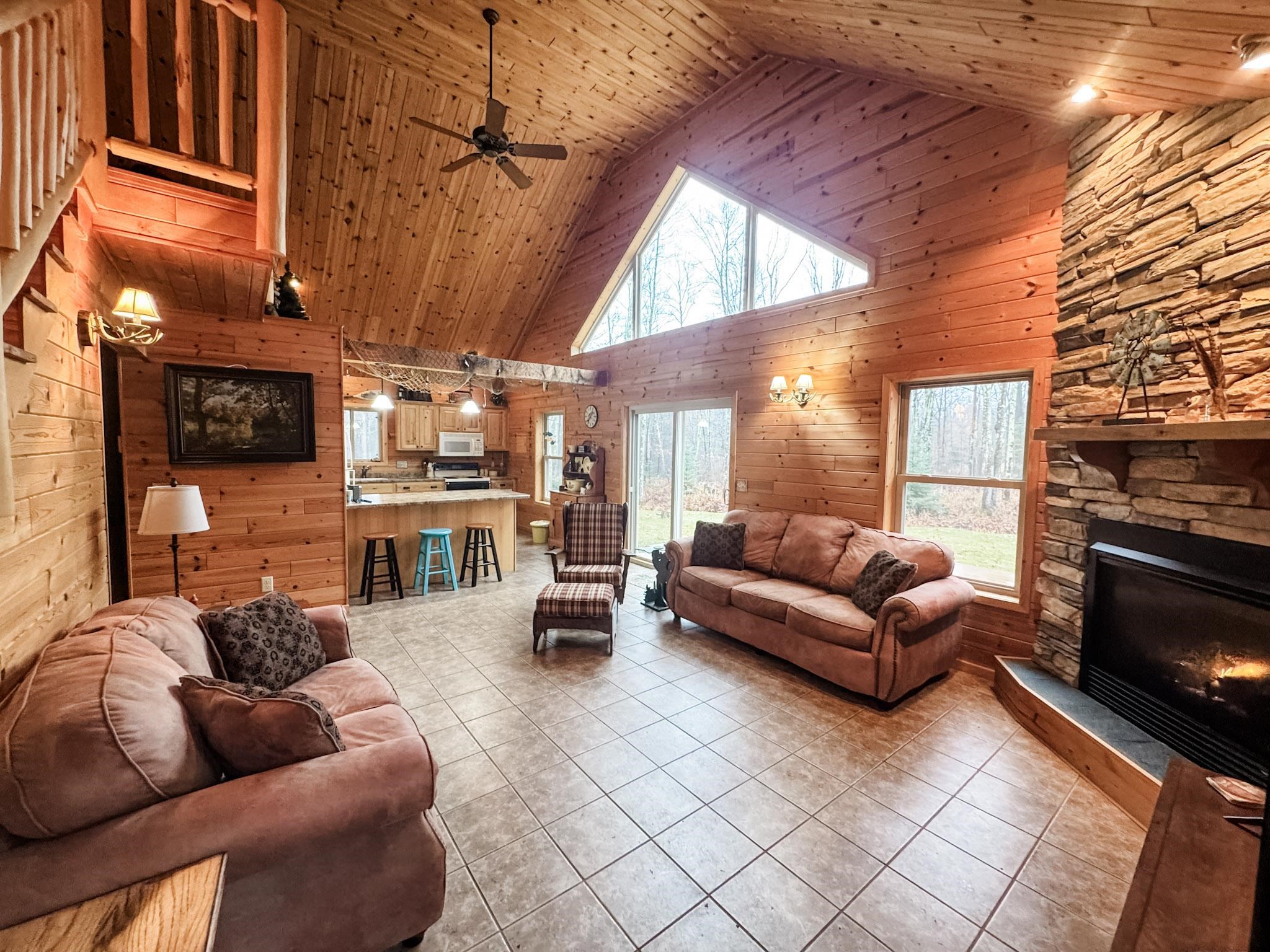 11466 Westerlund Loop Solon Springs, WI 54873 - Photo 11 of 55 Living area with wood walls, high vaulted ceiling, wood ceiling, light tile patterned flooring, and a fireplace