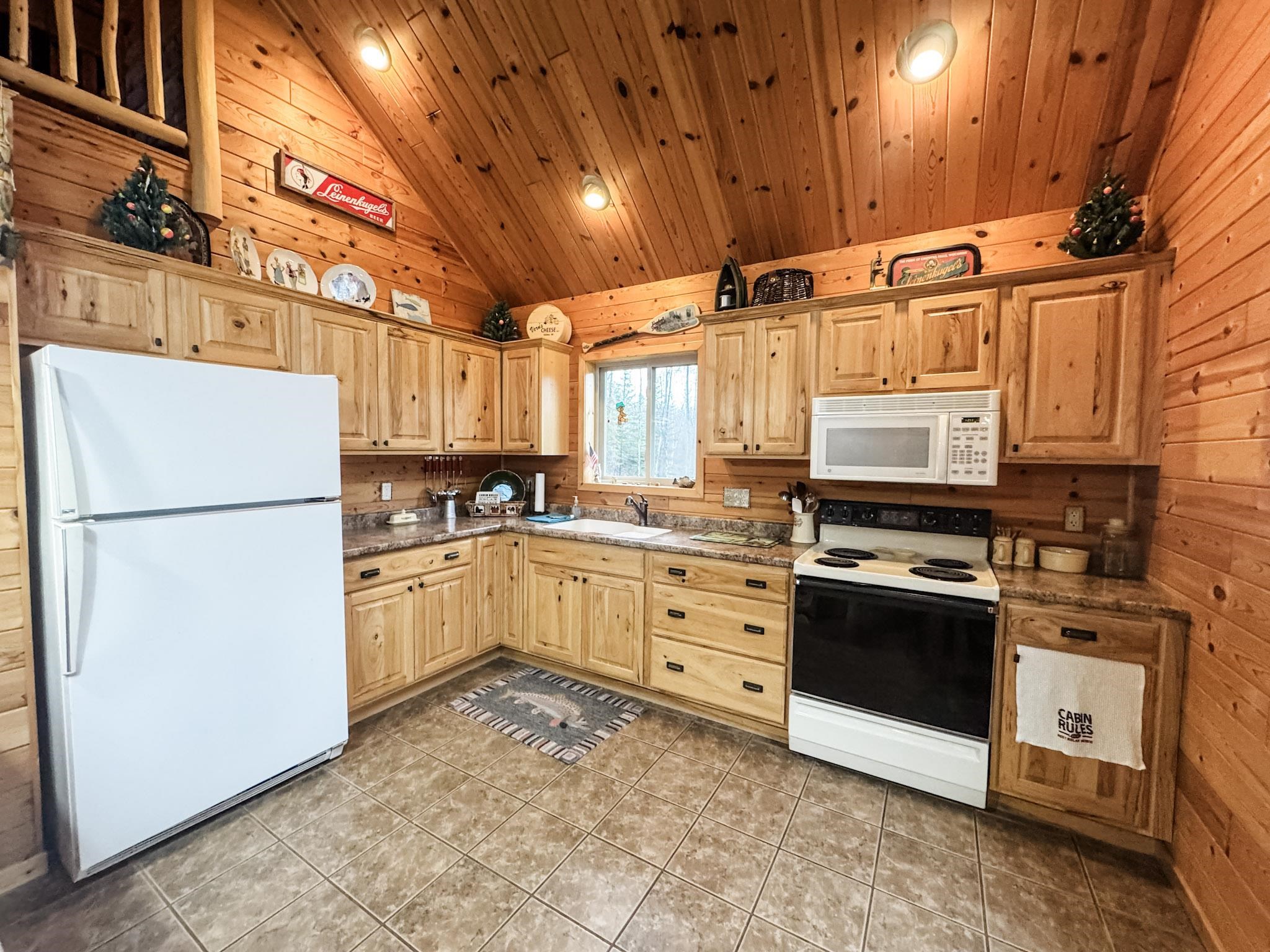 11466 Westerlund Loop Solon Springs, WI 54873 - Photo 17 of 55 Kitchen with wooden walls, white appliances, vaulted ceiling, light brown cabinetry, and wood ceiling