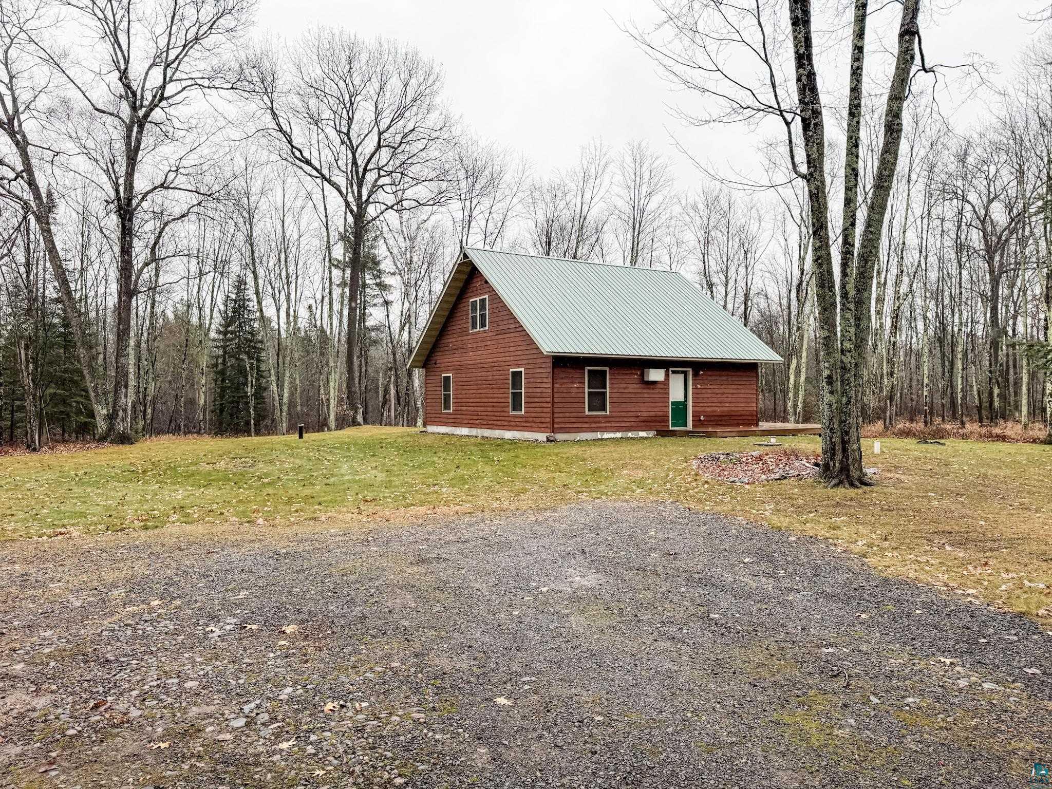 View of side of home featuring a lawn, a metal roof, and a wooded view