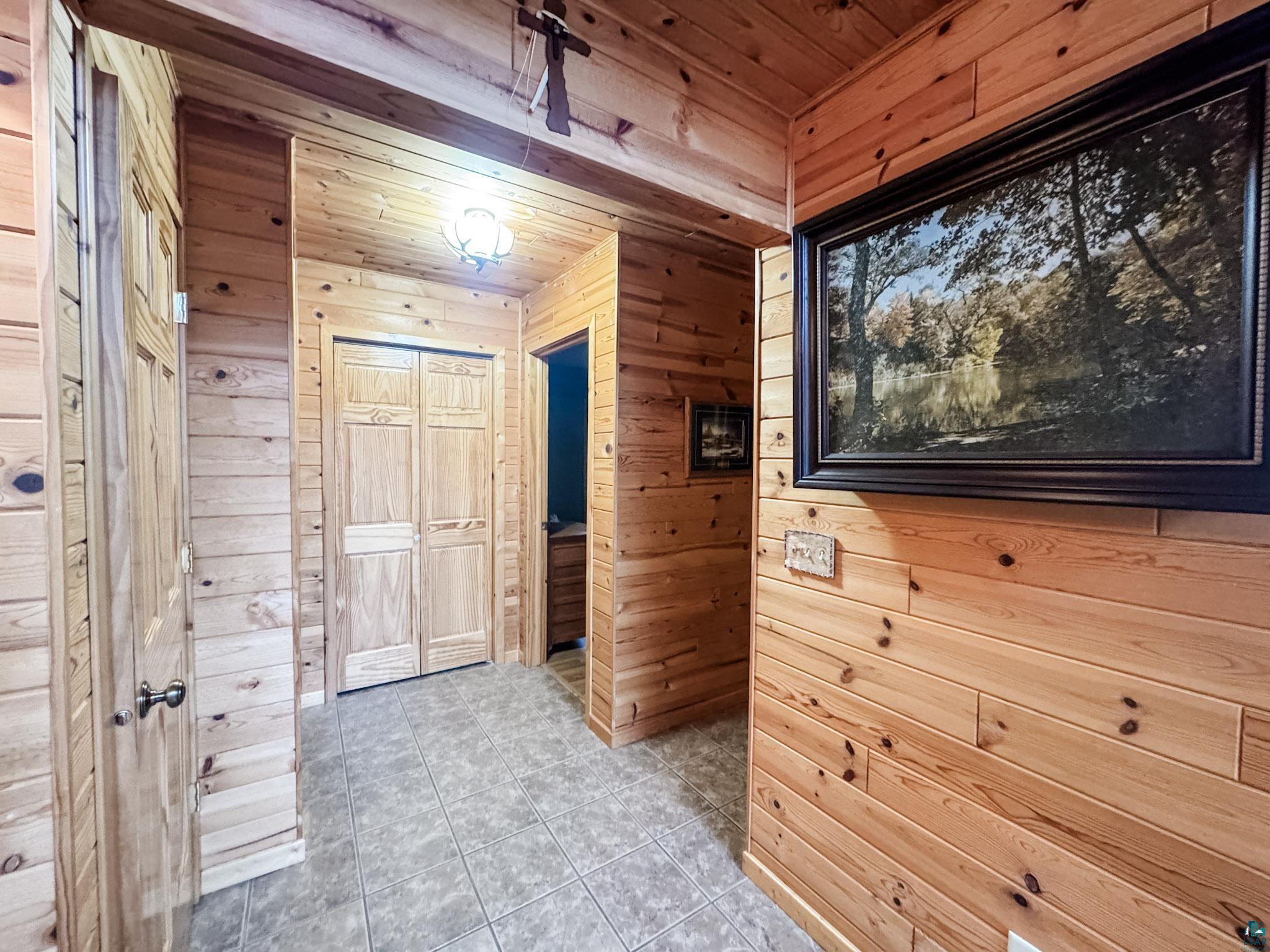 11466 Westerlund Loop Solon Springs, WI 54873 - Photo 38 of 55 Corridor featuring wood walls, tile patterned floors, and wood ceiling