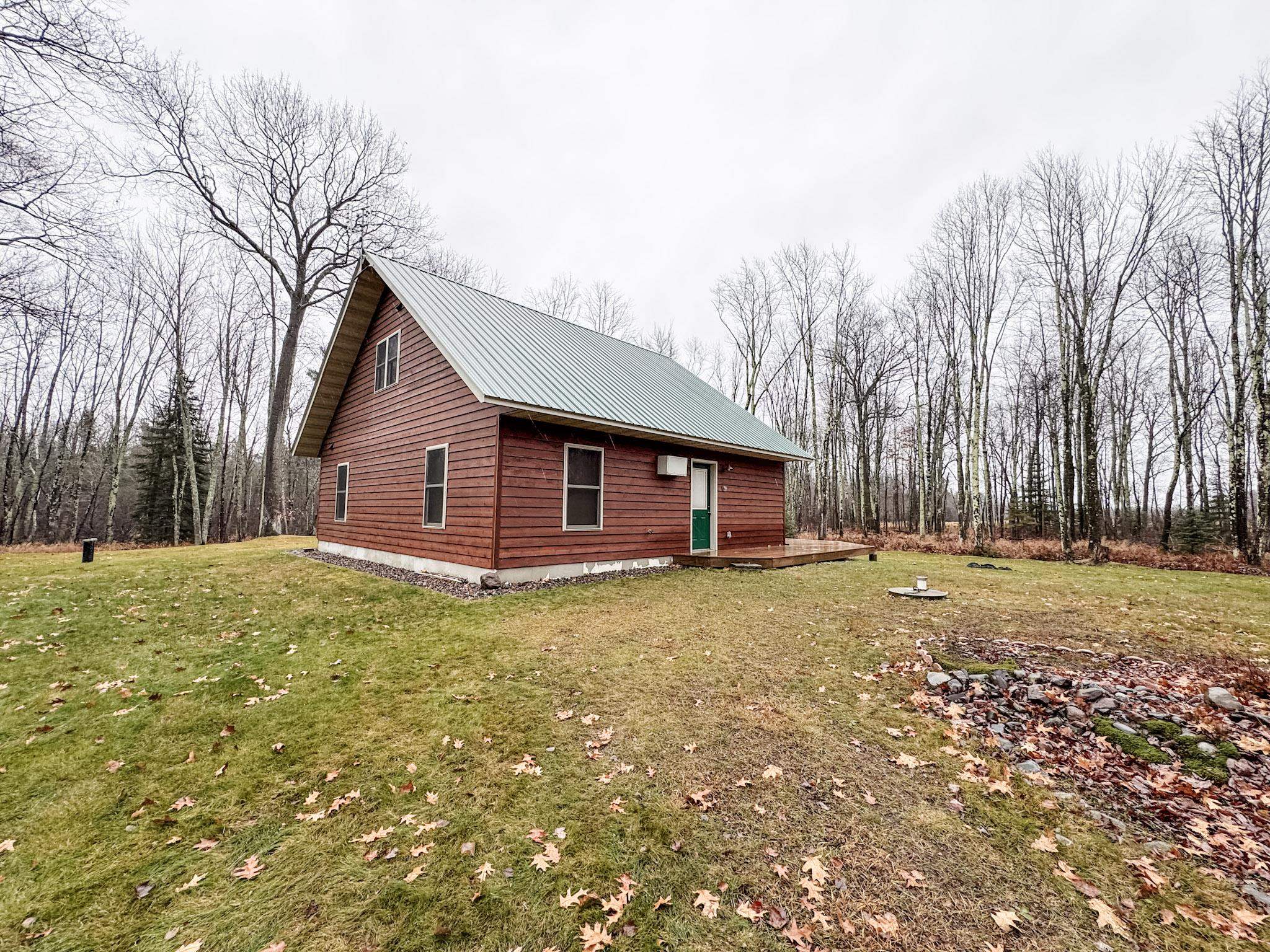 11466 Westerlund Loop Solon Springs, WI 54873 - Photo 50 of 55 View of side of home with a lawn and a metal roof