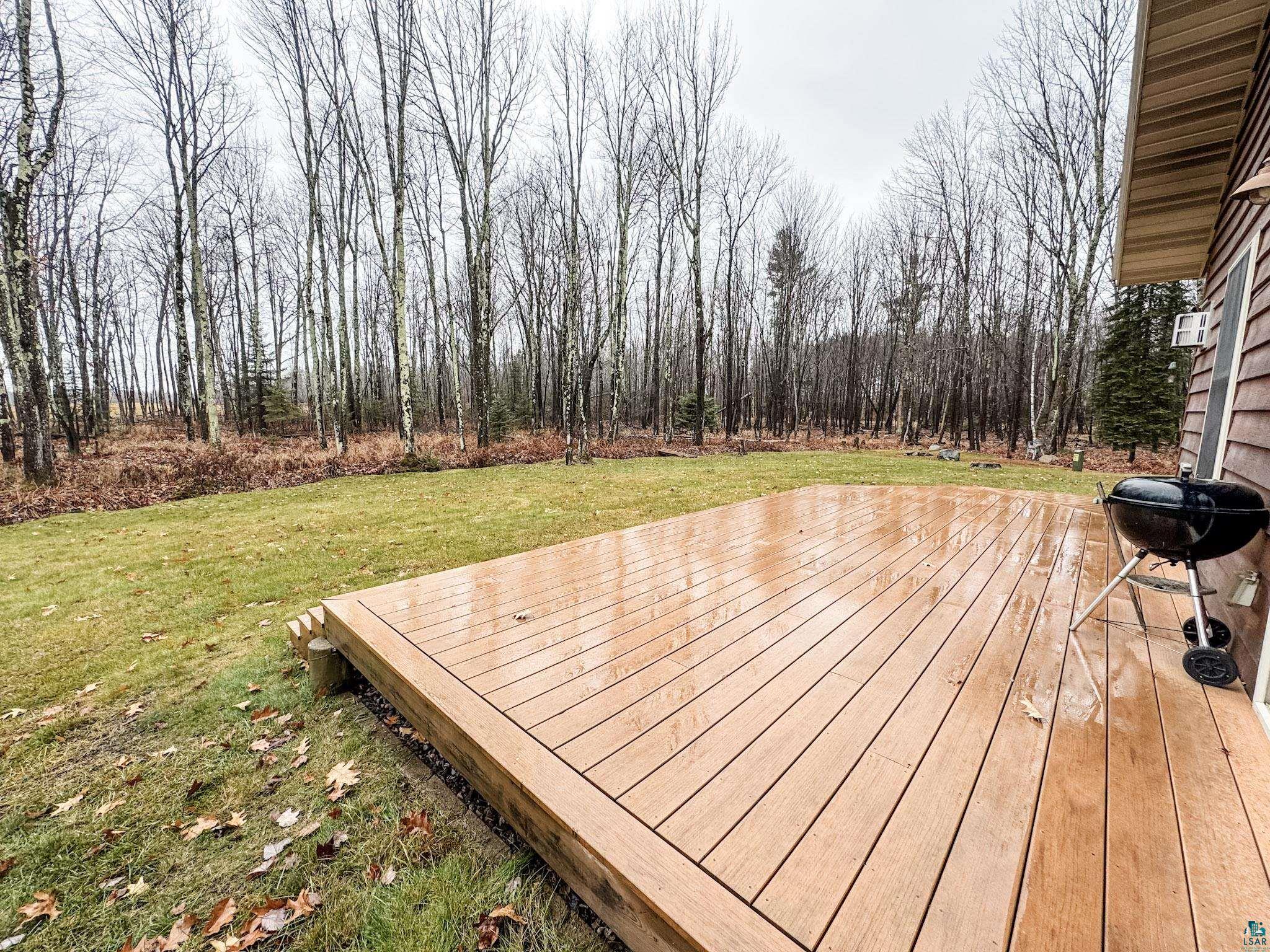 Wooden deck featuring a lawn and area for grilling