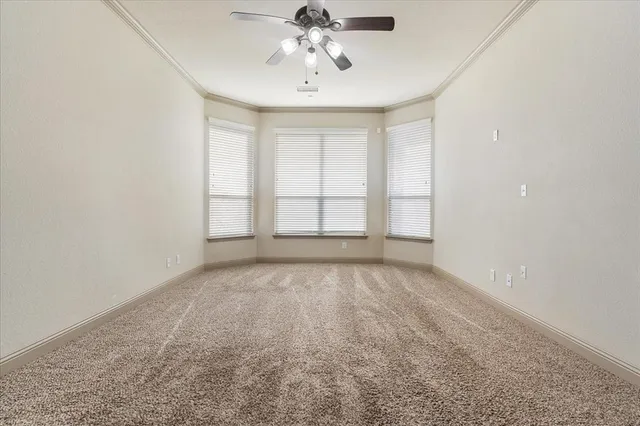 an empty room with chandelier fan and windows