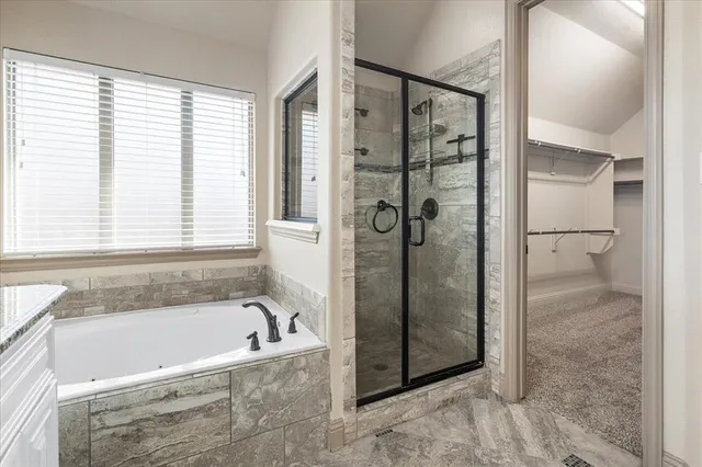a bathroom with a granite countertop sink a mirror a bathtub and shower