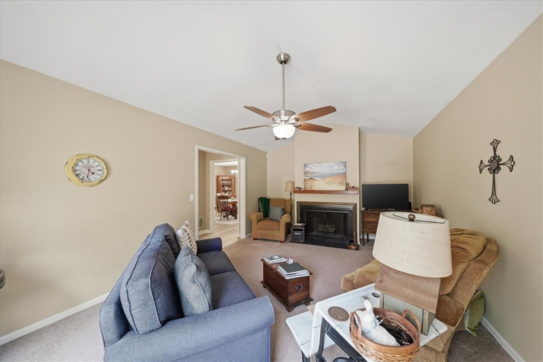 729 State Rd S-37-359 Seneca, SC 29672 - Photo 6 of 35 This inviting living space features a vaulted ceiling, a cozy fireplace, and soft carpet flooring.