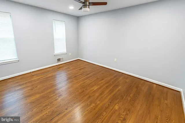 an empty room with a wooden floor and windows