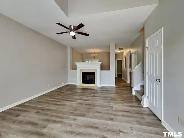a view of an empty room with wooden floor a fireplace and a window