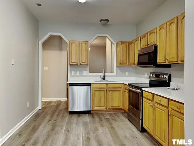 a kitchen with stainless steel appliances granite countertop a stove a sink dishwasher and a microwave oven with wooden floor