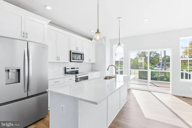 a large kitchen with stainless steel appliances a large counter top a stove a refrigerator a sink and a center island