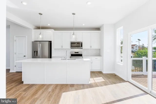 a kitchen with stainless steel appliances granite countertop a stove a refrigerator a oven and white cabinets with wooden floor