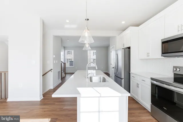 a large kitchen with kitchen island a stove a sink dishwasher and a oven with wooden floor