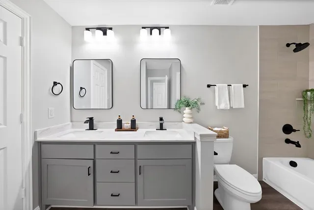 a bathroom with a double vanity sink mirror and toilet
