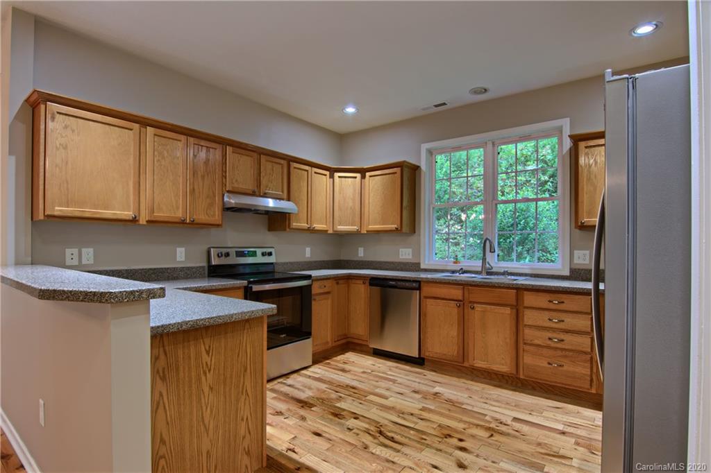 2322 Locust Grove Road Hendersonville, NC 28792 - Photo 10 of 40 a kitchen with stainless steel appliances granite countertop wooden cabinets a stove top oven a sink and dishwasher with wooden floor