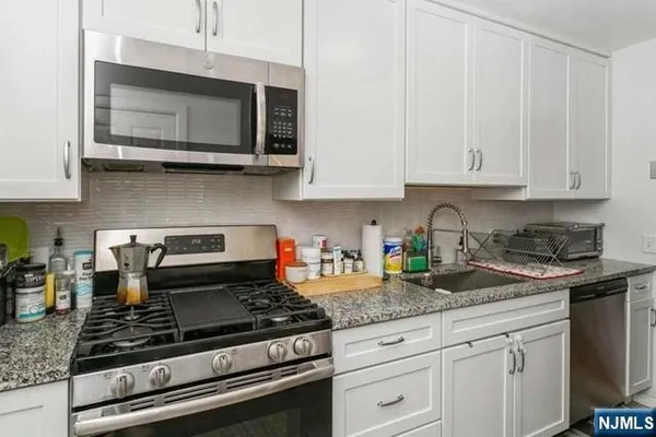 a kitchen with granite countertop white cabinets and stainless steel appliances