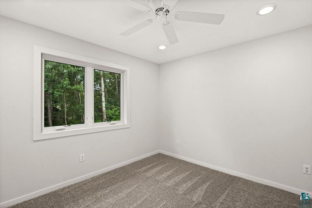 3971 Haines Road Hermantown, MN 55811 - Photo 25 of 34 Bedroom featuring a large window, neutral carpeting, white walls, a ceiling fan, and recessed lighting