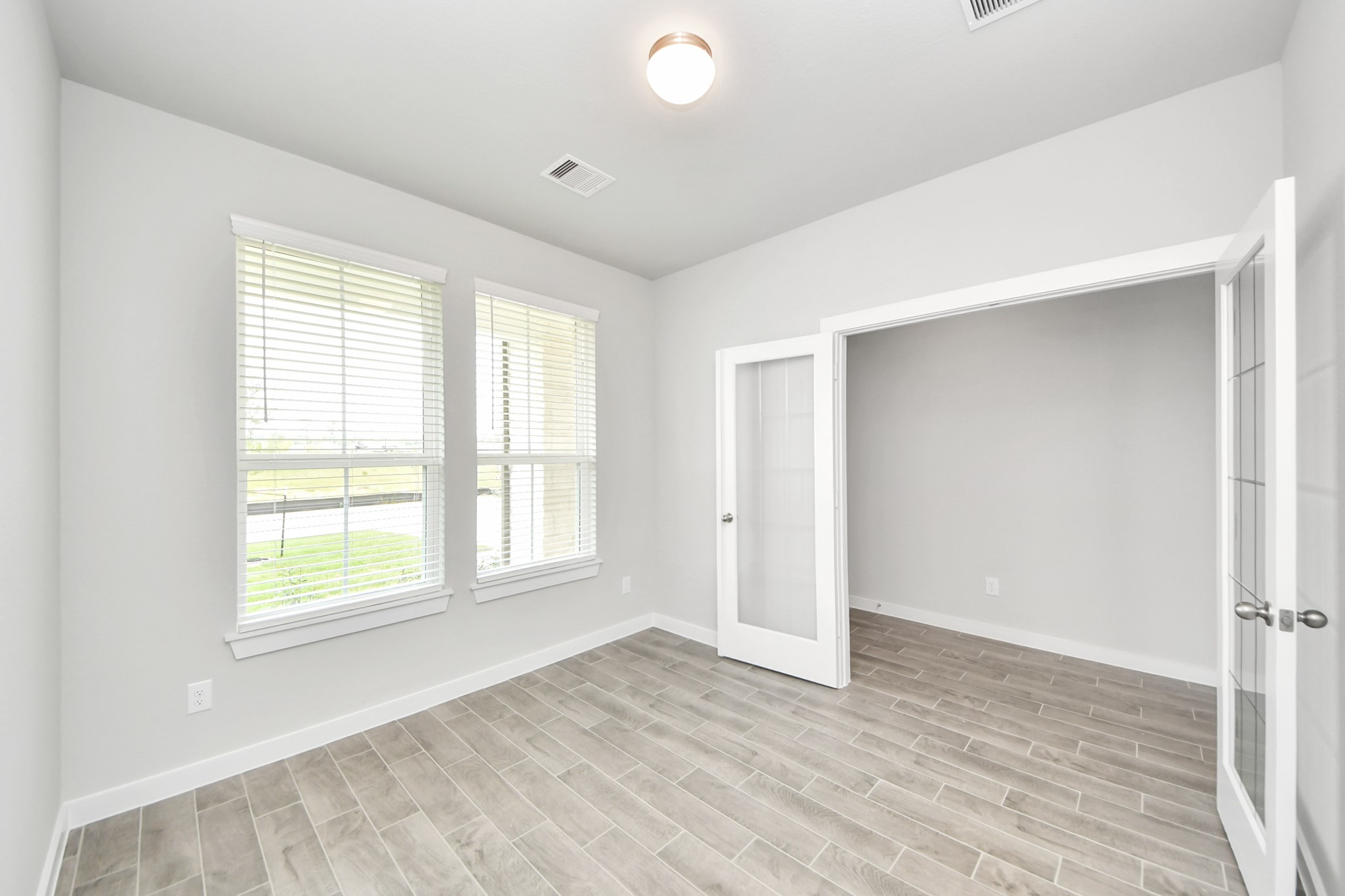 24502 Broad Park Spring, TX 77373 - Photo 7 of 47 Experience the perfect blend of sophistication and warmth in this home office, boasting elegant wood-look tile flooring and flooded with natural light from expansive windows and French doors.