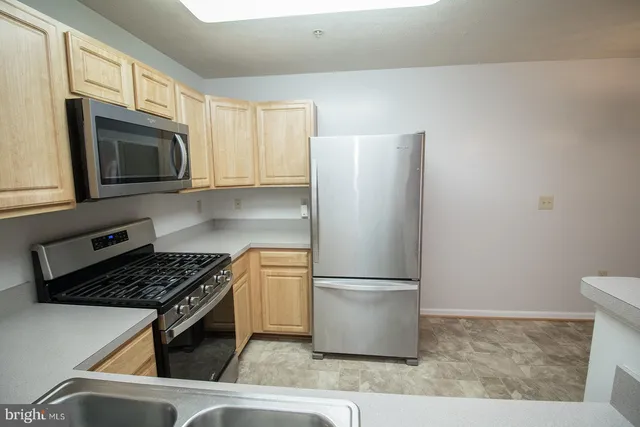 a kitchen with stainless steel appliances granite countertop a refrigerator stove top oven and sink