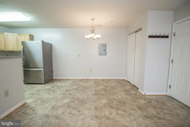 a view of a refrigerator in kitchen and an empty room