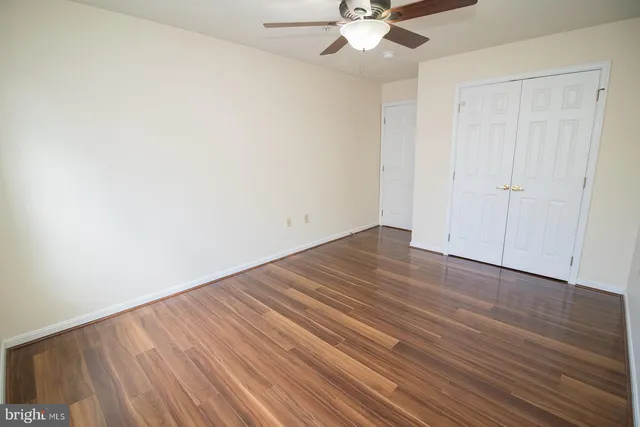 an empty room with wooden floor fan and windows