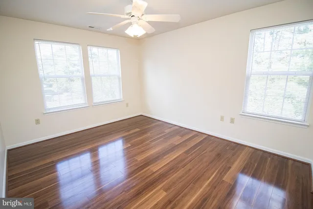 a view of empty room with wooden floor and fan